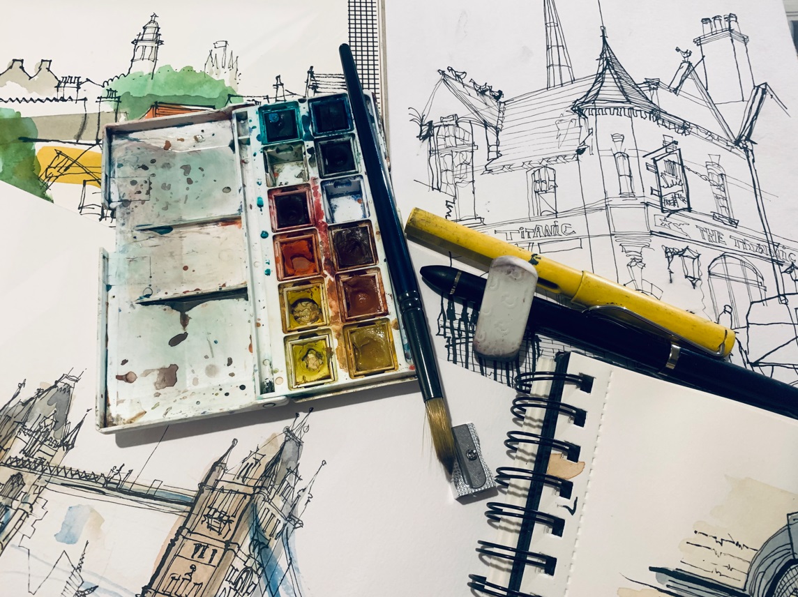 Sketchbooks with watercolour palette paint brush, pencil sharpener and pens